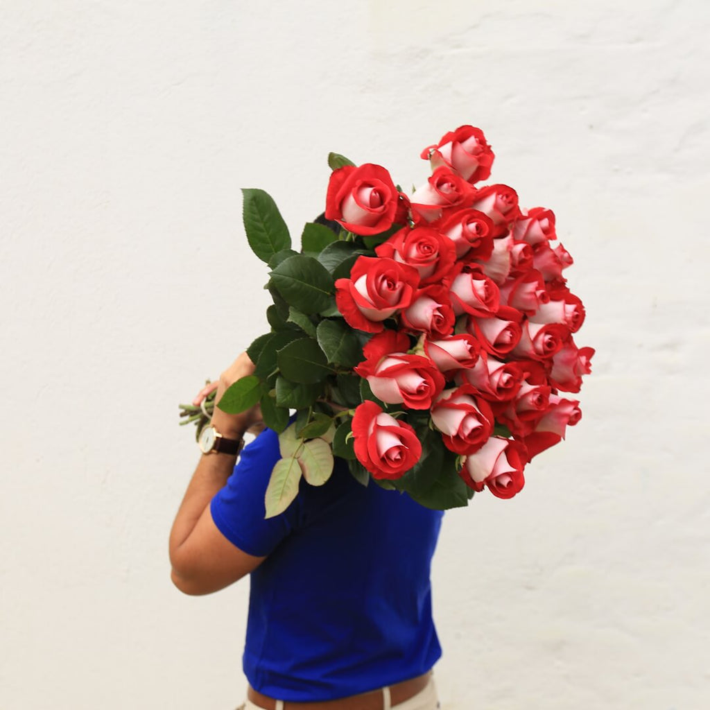A man is holding bouquet of extra long-stem roses