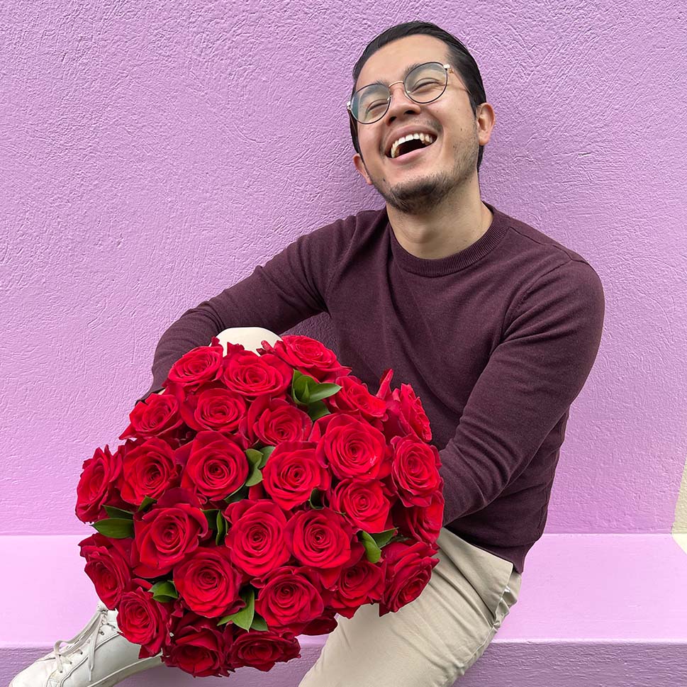 A man is holding a Classic Red Rose Bouquet by Rosaholics