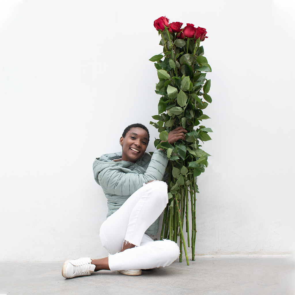 A girl is holding a bouquet of long-stem red roses 