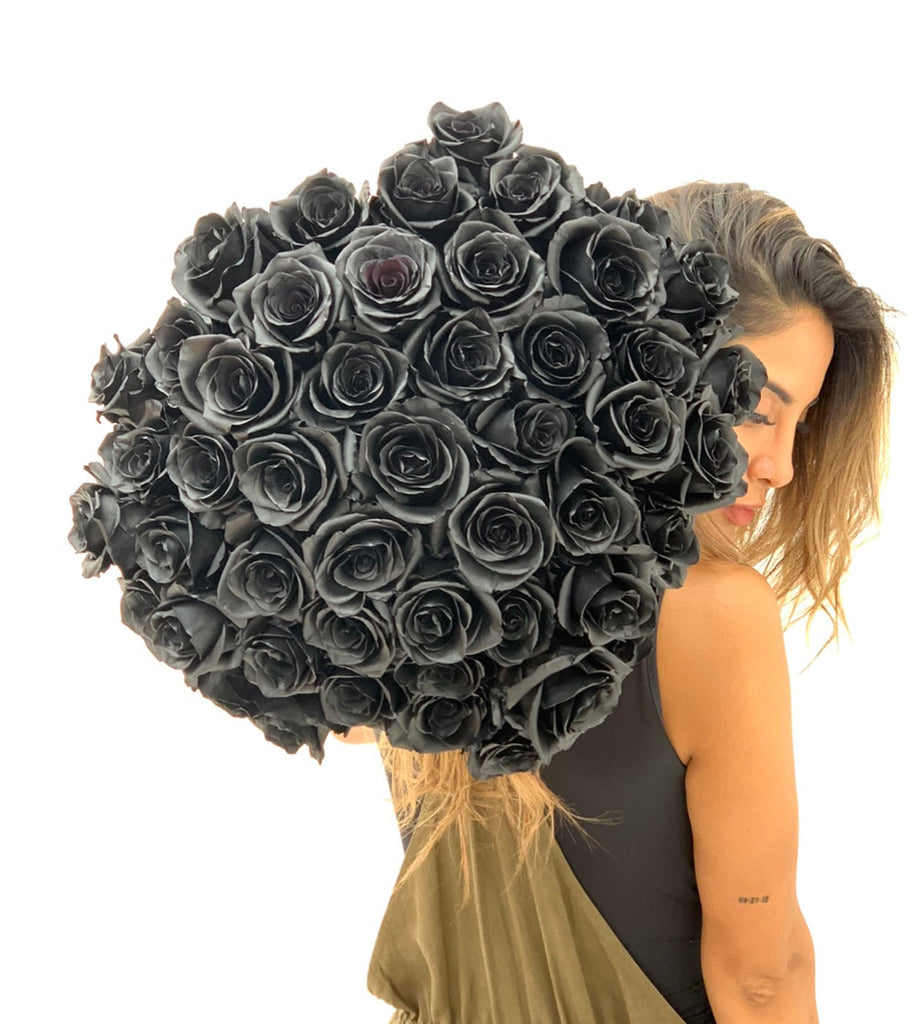 A young woman is holding a black rose bouquet