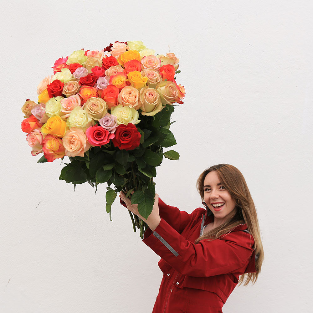 A girl is holding a bouquet of long-stems bright roses