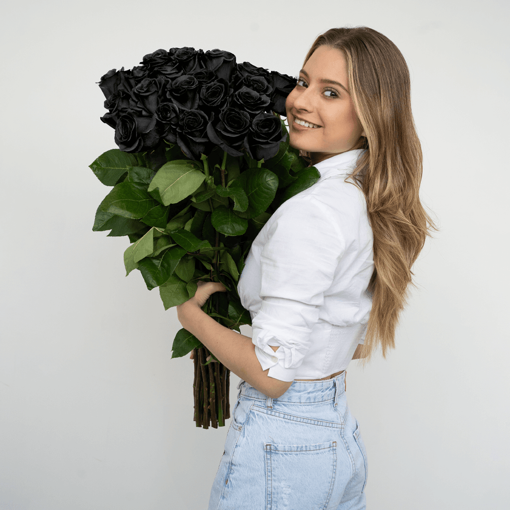 A woman holding a bouquet of black roses, called Black Mamba.