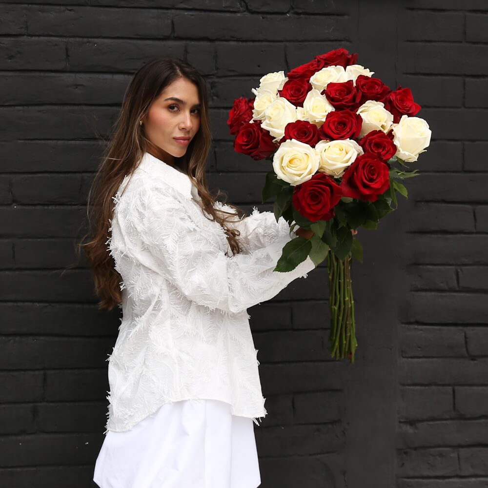 A woman is holding bouquet of extra long-stem red and white roses
