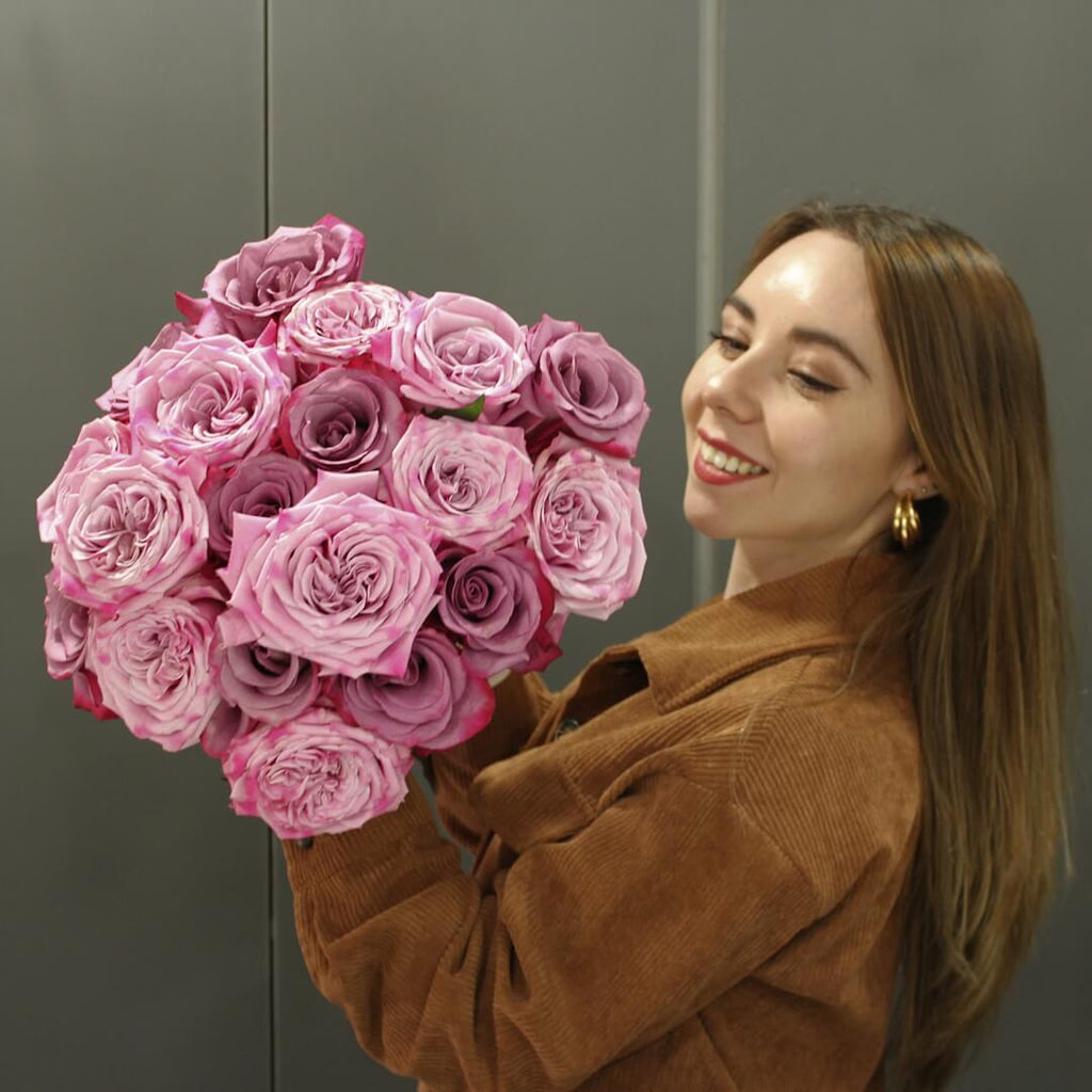 A girl is holding a Deep Purple and Pink Roses Bouquet
