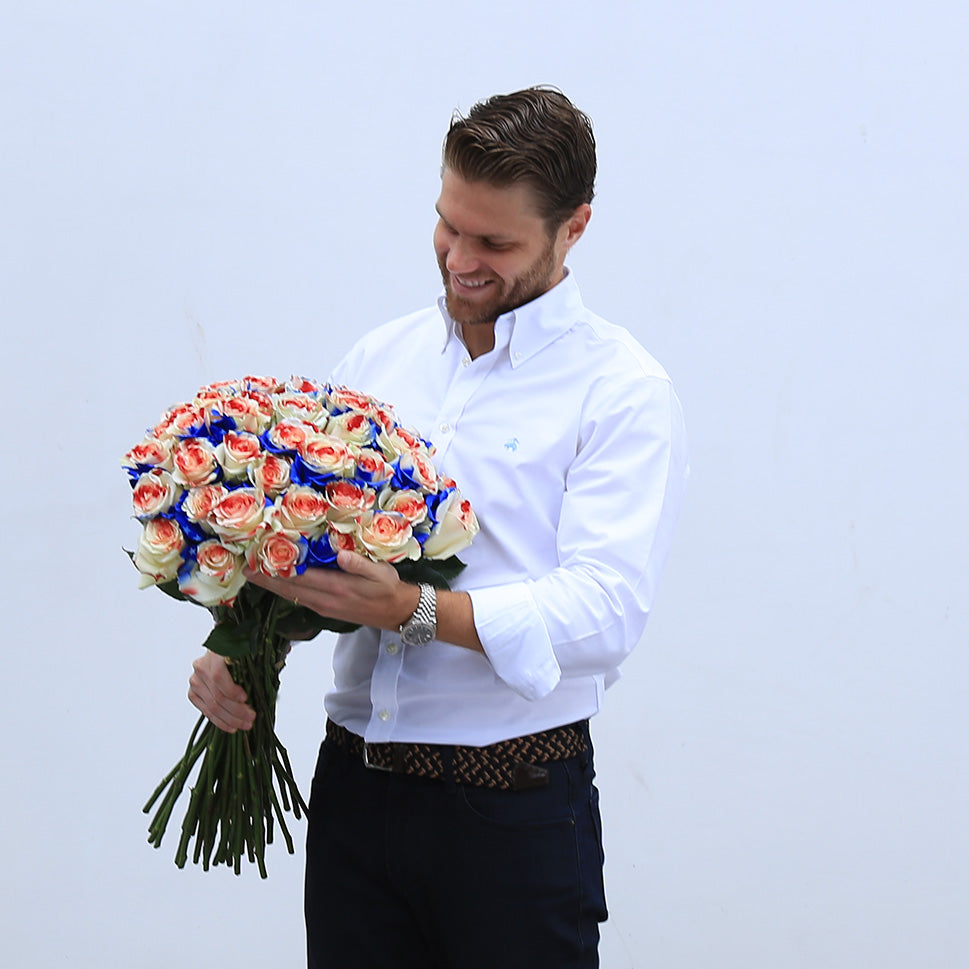 A man is holding bouquet of red, white and blue roses