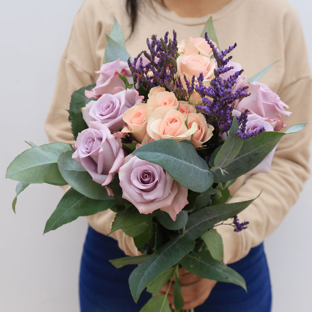Person holding a bouquet of pink and lavender roses