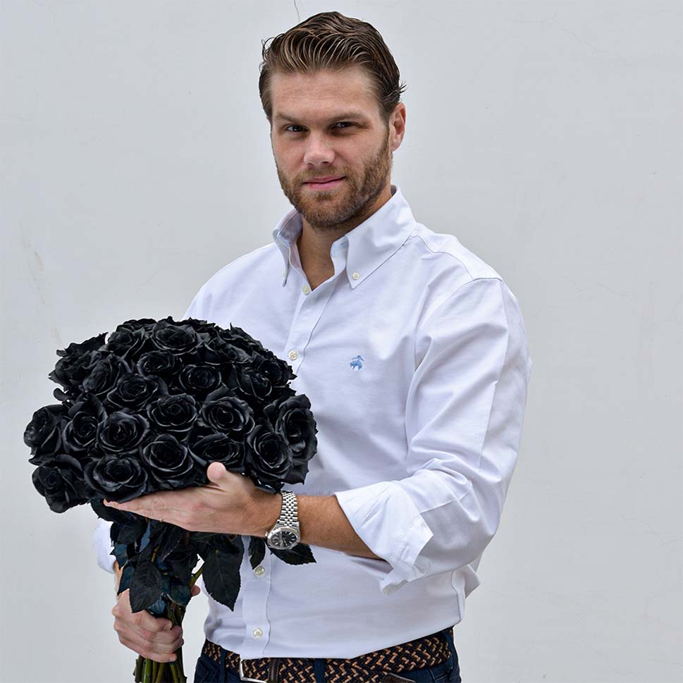 A man is holding a bouquet of black roses