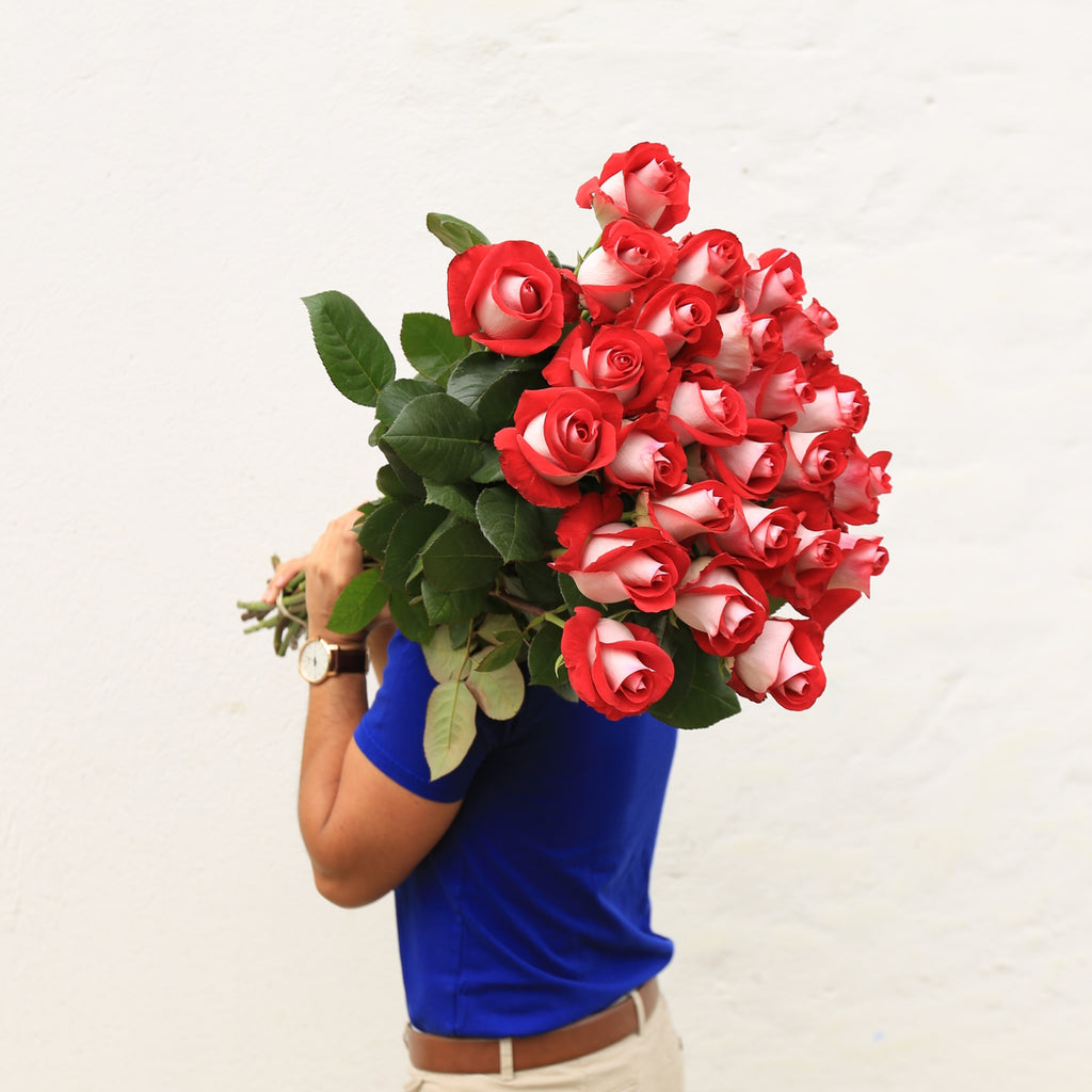 A man is holding bouquet of extra long-stem roses