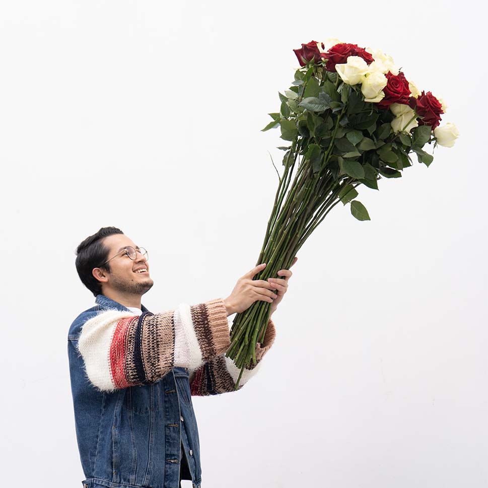 A man is holding bouquet of extra long-stem red and white roses