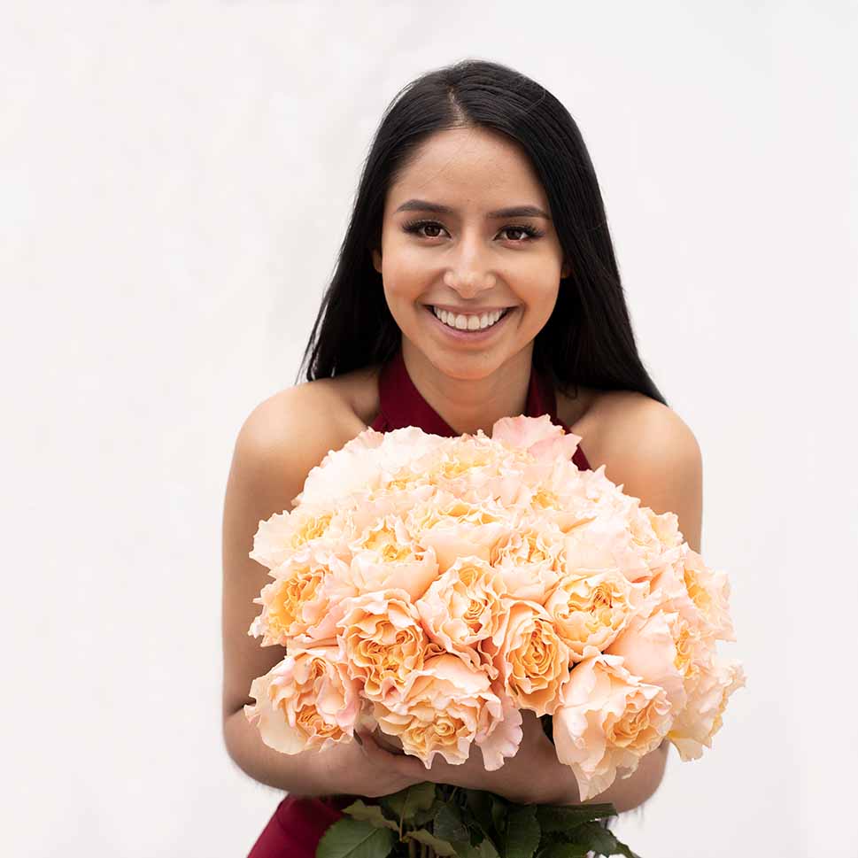 A young woman is holding a SUNSET GARDEN Rose Bouquet 