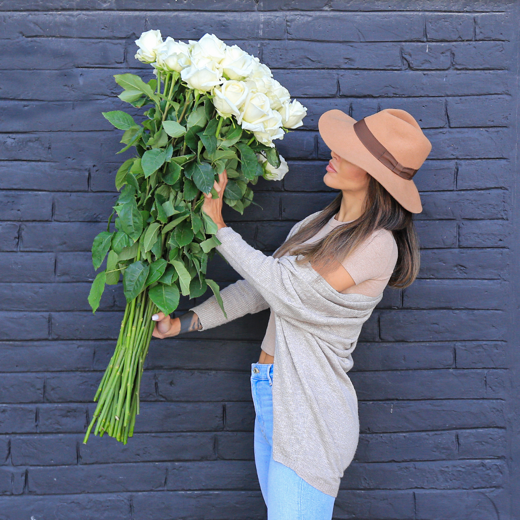 A girl is holding a bouquet of long-stem white roses